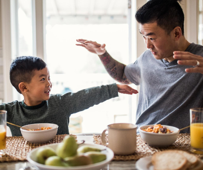 Father playing with young son at breakfast table
