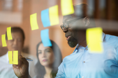 Man reviewing post-it-notes on glass wall