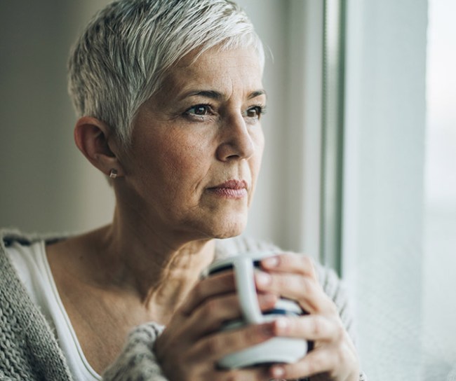 woman looking out the window with a cup of coffee