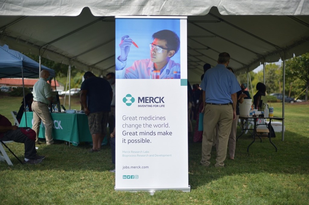 tent with Merck banner and people talking