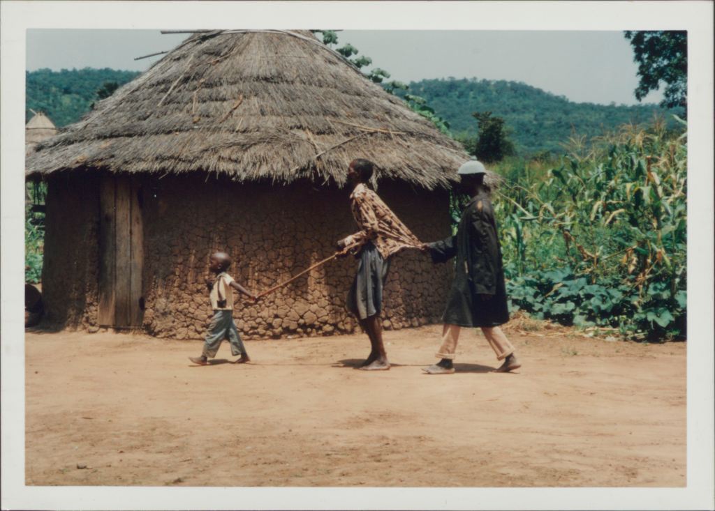 young boy leading older blind man with a stick