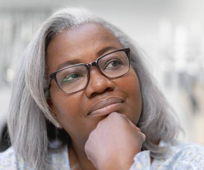 Woman leaning on her hand, looking up in and thinking