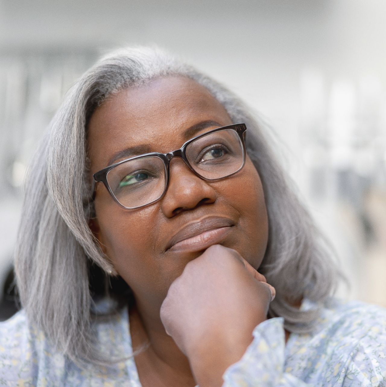Woman leaning on her hand, looking up in and thinking