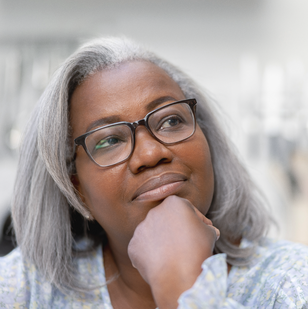 Woman leaning on her hand, looking up in and thinking