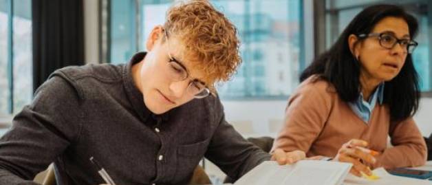 two students in classroom taking notes