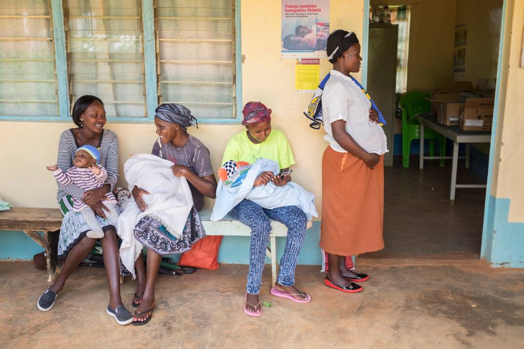 Women sitting on bench, holding babies