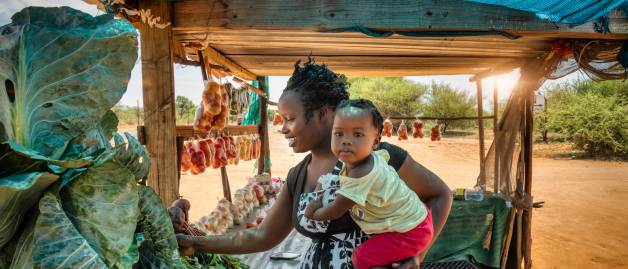 mother holding her child browsing street vendor
