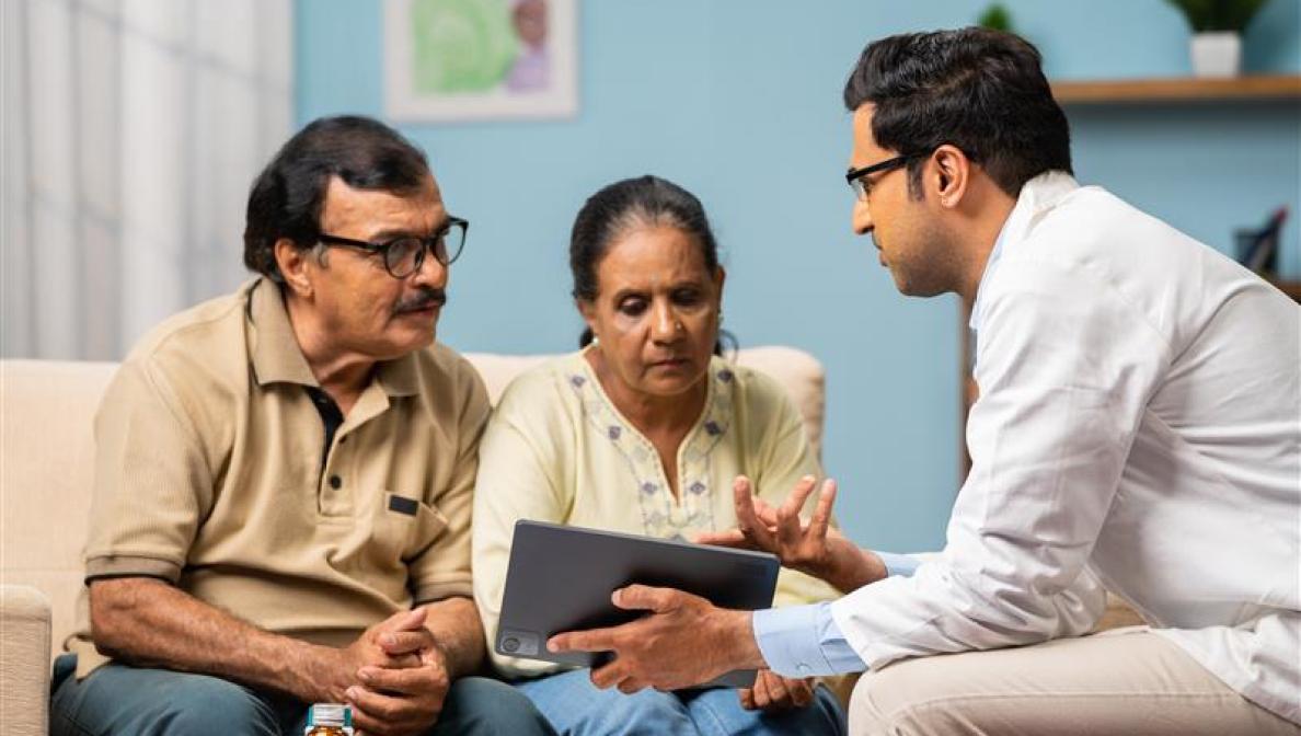 older man and woman talking with doctor and looking at an ipad