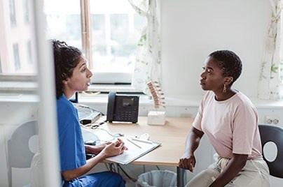 woman wearing pink shirt being consulted by a doctor