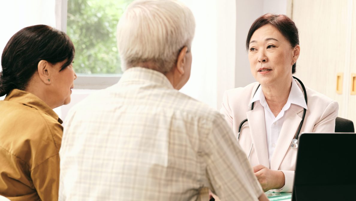 couple being consulted by a female doctor wearing a white coat