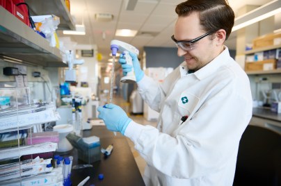 scientist working in a lab wearing white lab coat and blue gloves