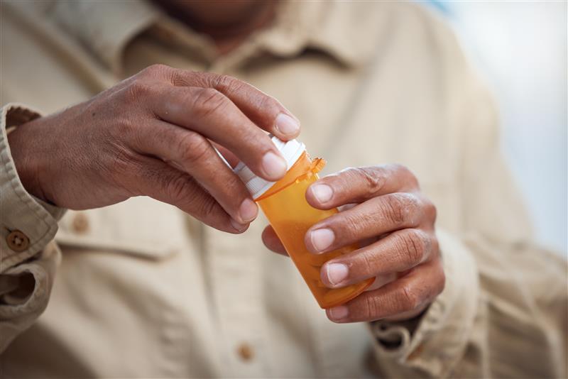 hands of an older person opening a medicine bottle