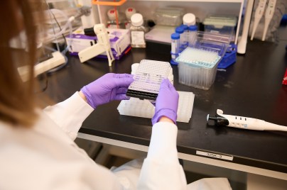 scientist in a lab wearing a lab coat and purple gloves working