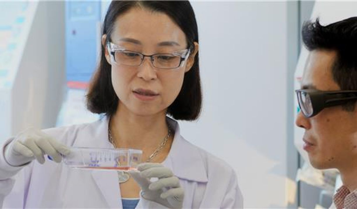 Two scientists looking at liquid in vial