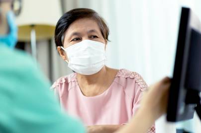 patient wearing a mask talking with a doctor