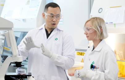 two scientists wearing lab coats and gloves working in a lab
