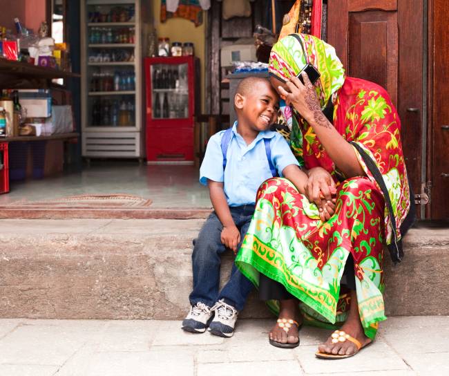 Parent and child talking and smiling at an East African market.