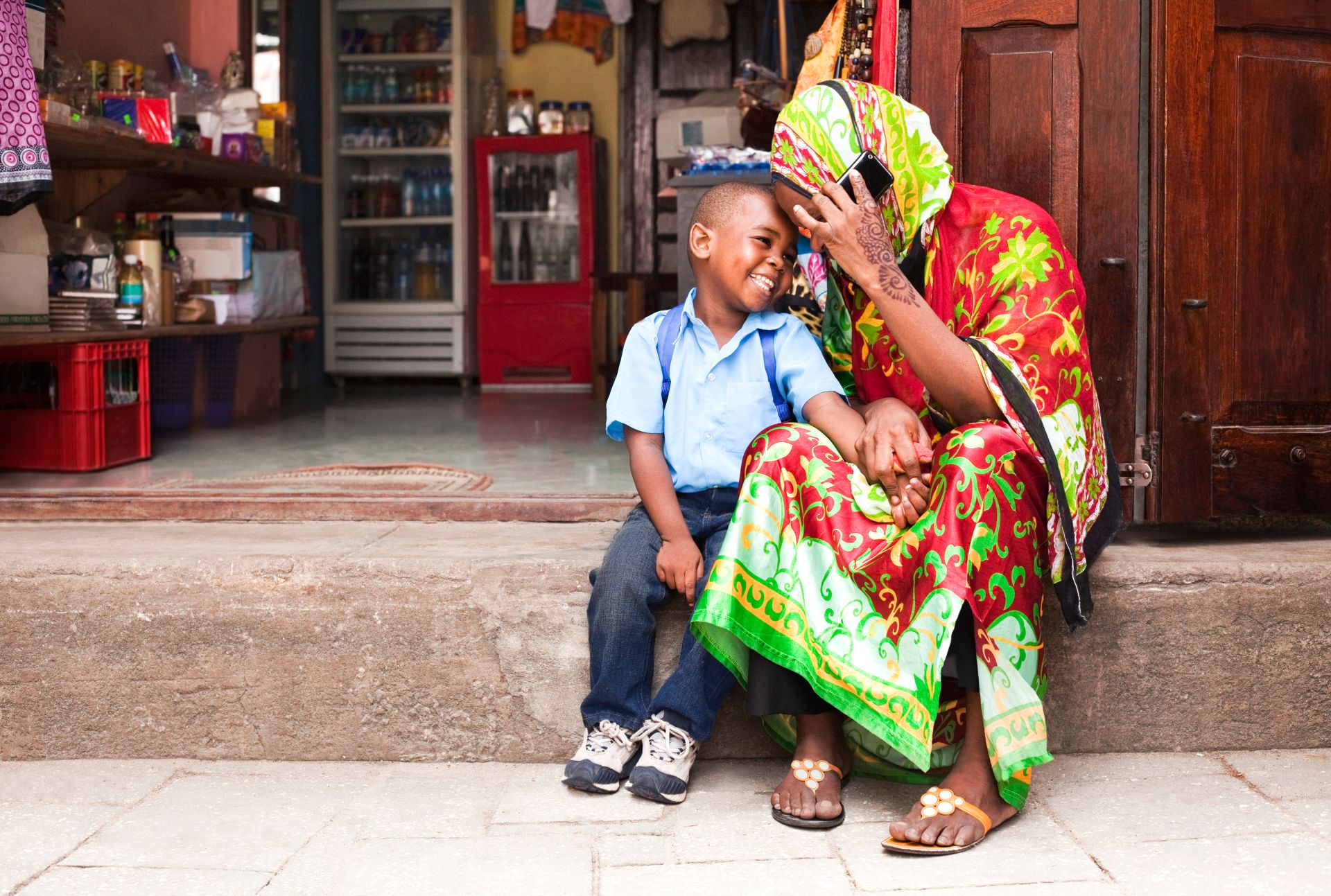 Parent and child talking and smiling at an East African market.