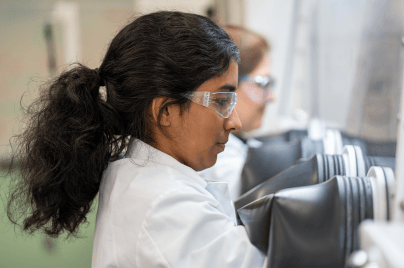 Scientist wearing lab coat and glasses looking into tube