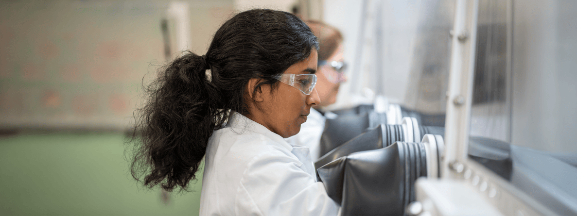 Scientist wearing lab coat and glasses looking into tube