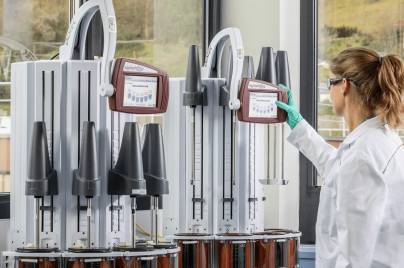 scientist in a lab with white lab coat, gloves and goggles workint with equipment