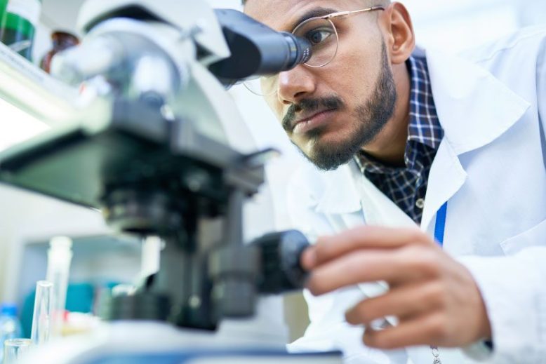 Scientist in a lab looking through microscope