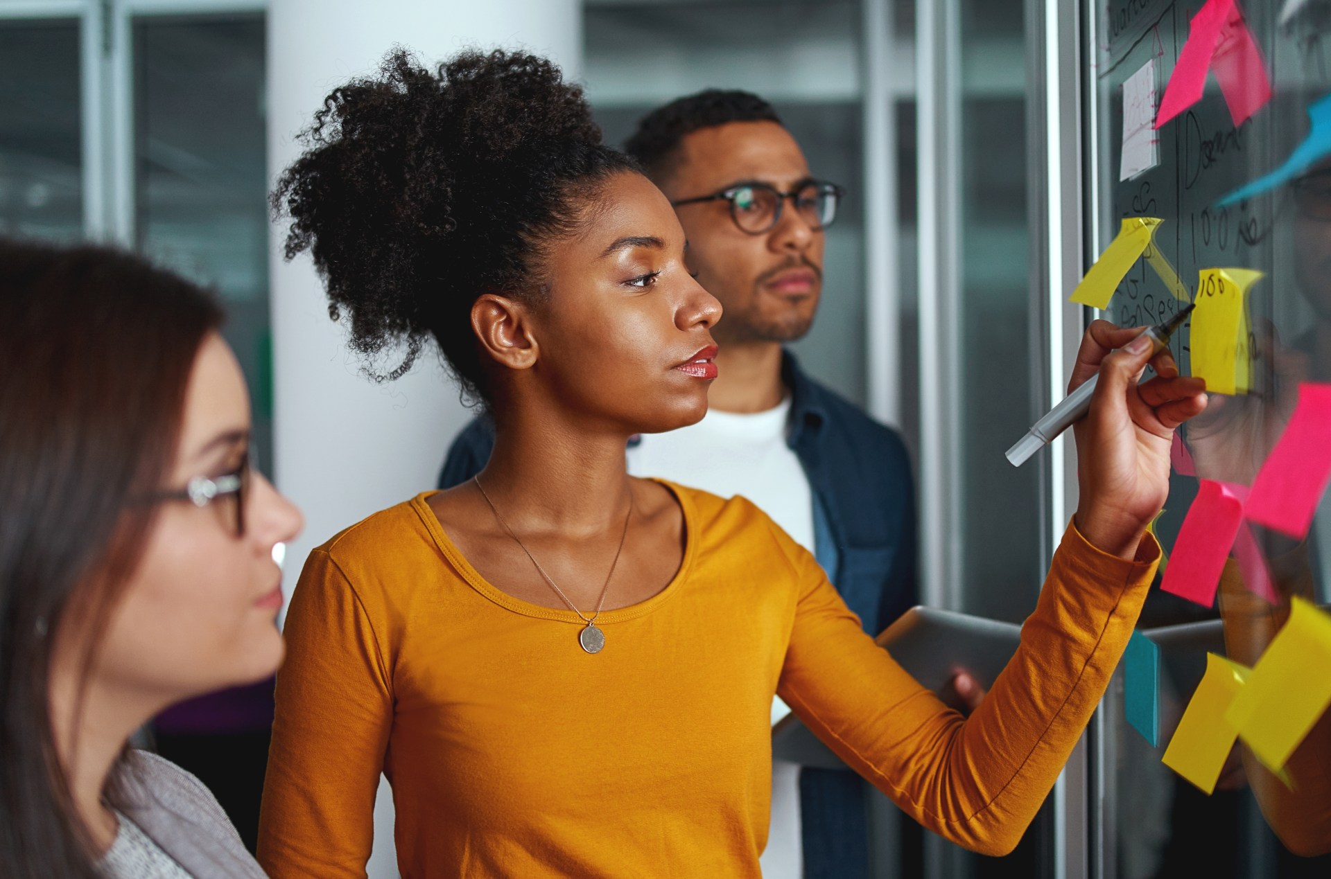Diverse people looking at board with sticky notes