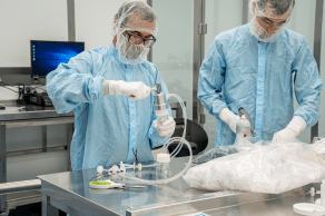 two individuals in protective gear operating in the lab