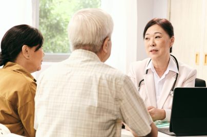 couple being consulted by a female doctor wearing a white coat