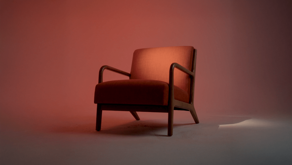 a single red chair with arm rests and a spotlight on it